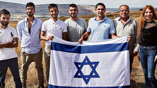 Grupo de jóvenes árabes israelíes sosteniendo una bandera israelí. 