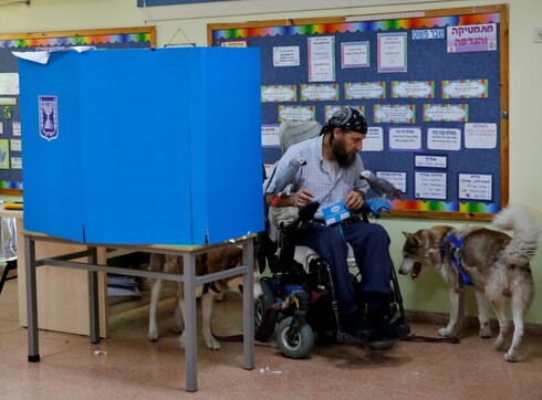 Un hombre en silla de ruedas asiste a la urna junto a sus perros y un loro