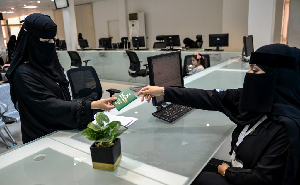 Una empleada saudita entrega un pasaporte a una mujer 