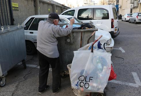 Un anciano busca botellas de plástico en la basura para intercambiarlas por dinero 