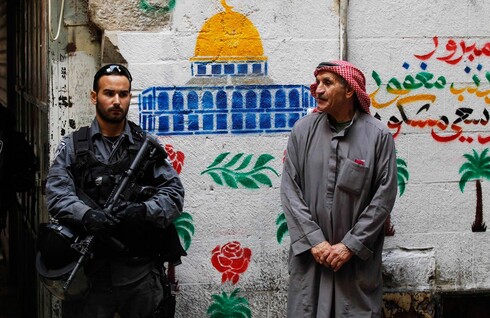 Un oficial de la Policía de Fronteras se encuentra al lado de un residente musulmán local en Jerusalem Este 