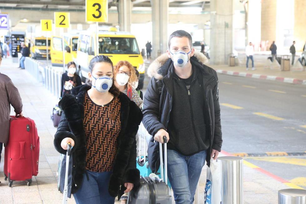 Viajeros llegan al aeropuerto Ben Gurión provistos de máscaras.