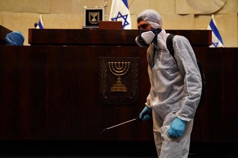 Un trabajador rocía desinfectante contra el coronavirus dentro de la Knesset