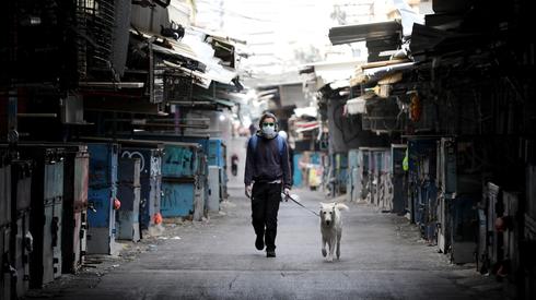Un hombre pasea su perro cerca de los puestos normalmente abarrotados de gente del Mercado Carmel, en Tel Aviv. 