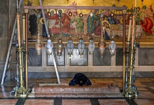 Un adorador solitario reza por la Piedra de la Unción en la Iglesia del Santo Sepulcro en la Ciudad Vieja de Jerusalem. 