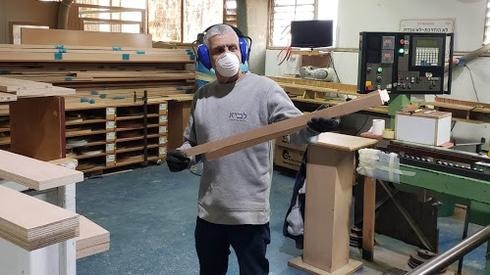 Un carpintero del kibutz Lavi usa una máscara protectora mientras construye muebles para sinagogas. 
