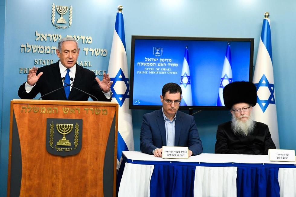 El primer ministro Benjamin Netanyahu se dirige al público, junto con el ministro de Salud, Yaakov Litzman, a la derecha, y la DG del Ministerio de Salud, Moshe Bar-Siman-Tov. 