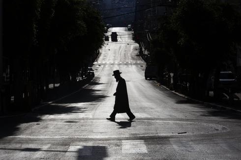 Un judío ortodoxo cruza una calle principal desierta debido a las medidas del gobierno para ayudar a detener la propagación del coronavirus, en Bnei Brak. 