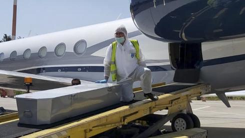 Un miembro del equipo voluntario de emergencia de ZAKA descarga un ataúd de un avión en el aeropuerto Ben Gurion en Israel 