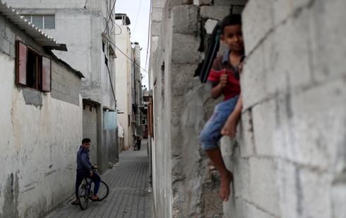 Un joven palestino en bicicleta observa a un niño sentado en una pared en el campo de refugiados de Jabalia. 