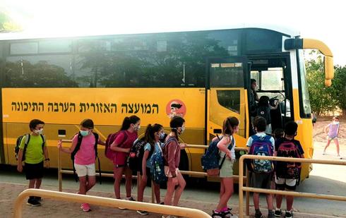 Alumnos israelíes abordan un autobús escolar cubriendo sus rostros con máscaras de protección.