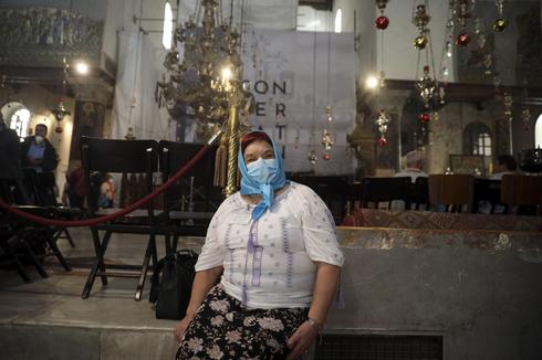 Una mujer utiliza una máscara de protección en la Basílica de la Natividad antes del cierre del 5 de marzo. 