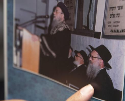 El rabino Levi Banon señala una foto que muestra al rabino Sholom Eidelman, quien murió recientemente después de contraer el coronavirus 