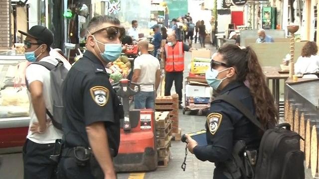 Policía controla la utilización de mascarillas en un mercado israelí. 