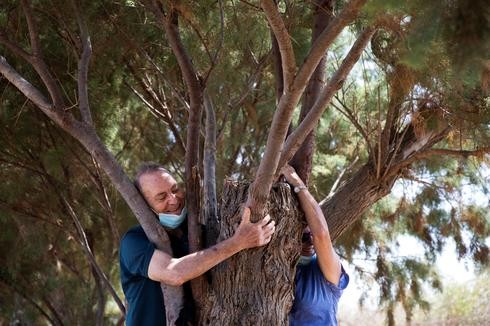 Una pareja abraza un árbol en un paseo organizado por la Autoridad de la Naturaleza y Parques de Israel.