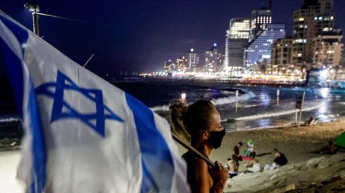 Una manifestante lleva una bandera de Israel en una protesta en Tel Aviv. 