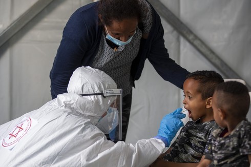 Un trabajador de la salud evalúa a un niño para detectar coronavirus en un centro de pruebas para migrantes en Tel Aviv. 