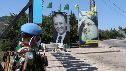 Un soldado de las Naciones Unidas junto a un cartel que representa al líder libanés del Hezbollah, Hassan Nasrallah. 