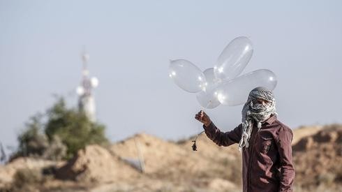 Un terrorista en Gaza se prepara para lanzar un dispositivo incendiario hacia Israel, usando lo que parece ser un simple globo con helio.
