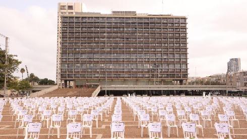 Instalación de sillas vacías con la Municipalidad de Tel Aviv de fondo. 