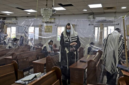Ortodoxos rezan separados por láminas de plástico en una sinagoga de Bnei Brak.