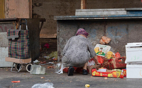 Una mujer buscando comida en la basura, cerca del mercado Carmel de Tel Aviv.