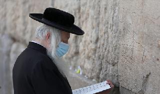 Un hombre ortodoxo reza en el Muro de los Lamentos con máscara de protección.