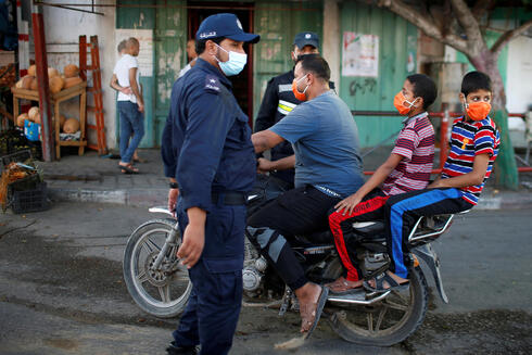 Un hombre en moto con sus hijos, la policía que controla; todos en Gaza usan barbijos para protegerse del contagio. 