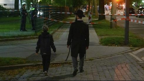 Un hombre ortodoxo camina junto su hijo a pocos metros de la sinagoga de Hamburgo, frente a la cual ocurrió el brutal ataque antisemita. 