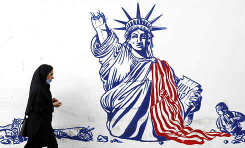 Una mujer iraní pasa frente a un mural que muestra la Estatua de la Libertad desfigurada en el muro de la antigua Embajada de Estados Unidos en Teherán. 