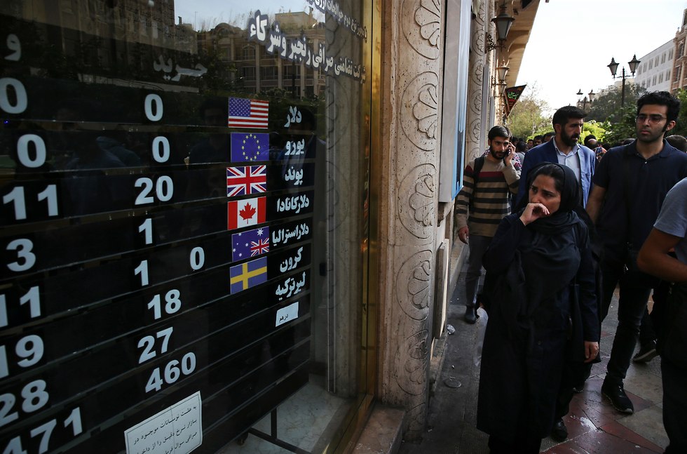 Iraníes observan el valor de las monedas extranjeras en una casa de cambio en Teherán.