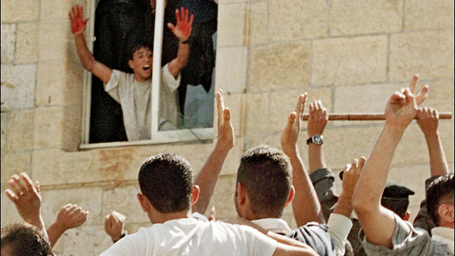 En el año 2000, en la ventana de una comisará de Ramallah, un palestino muestra sus manos ensagrentadas con la sangre de dos soldados israelíes. 