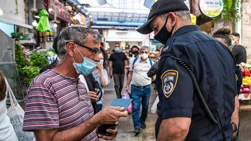 Uma polícia aplica as diretrizes de saúde em Jerusalém. (Shalev Shalem) ano