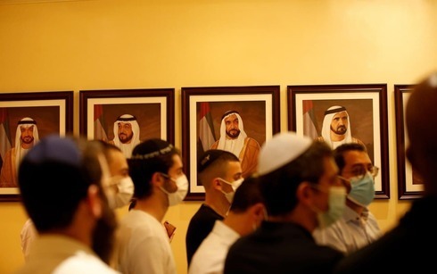 Ciudadanos israelíes con barbijo pasan frente a retratos de jeques en un museo de Dubai. 