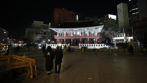 Ciudadanos coreanos caminan frente al pabellón de Bosingak donde se canceló su ceremonia anual de campana de Nochevieja en Seúl. 