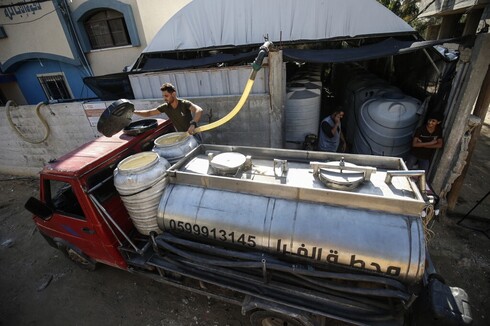 Un trabajador palestino llena un camión que transporta agua de una planta de agua dulce que extrae agua de las napas. 