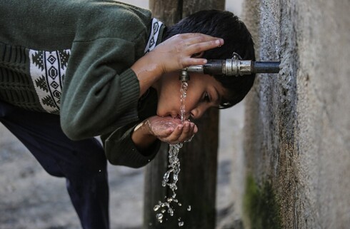 Uma criança palestina bebe água da torneira na cidade de Khan Yunis, no sul da Faixa de Gaza. (AFP) água potável