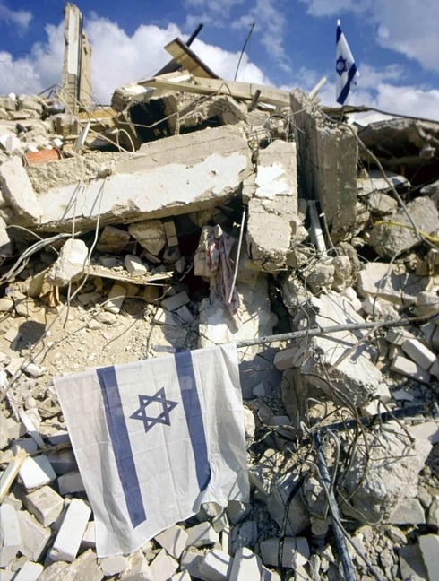 La bandera israelí se alza por sobre los escombros de la destrucción de un misil. 