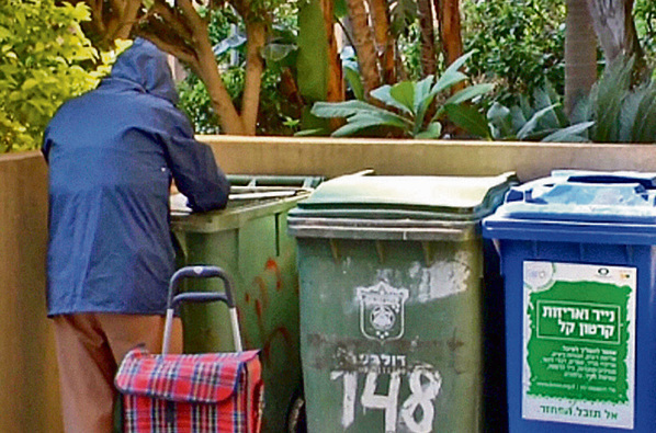 Un anciana israelí busca comida en los contenedores de basura.