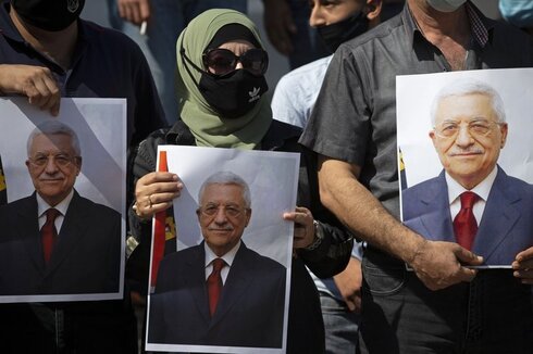 Ciudadanos palestinos con carteles que tienen impresa la foto del presidente palestinos, Mahmoud Abbas. 
