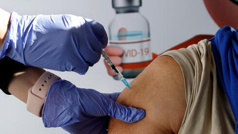 Um profissional da área da saúde administra a vacina contra a COVID-19.