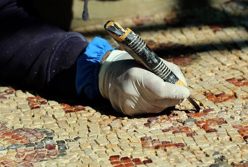 Los trabajadores restauran meticulosamente un piso de mosaico en la iglesia de San Juan Bautista, construida en el año 619 de nuestra era. (AFP) Jordania UNESCO