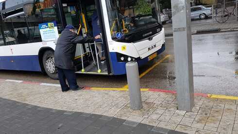Un anciano israelí intentando abordar el transporte público. 