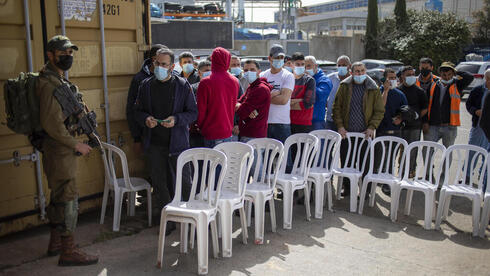 Trabajadores palestinos esperan para vacunarse en un paso fronterizo hacia Israel. 