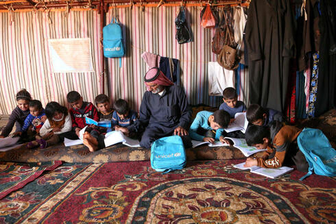 Al-Khatun junto a sus nietos, que estudian de un libro de texto. 