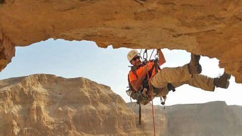 Un arqueólogo desciende en rappel por el acantilado hacia la Cueva del Horror en el desierto de Judea.