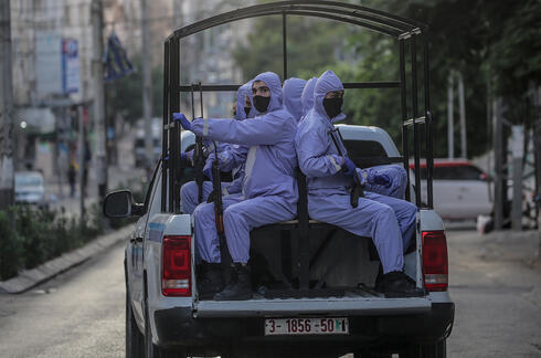 Miembros de las fuerzas de seguridad de Hamás con trajes protectores patrullan las calles de Gaza durante la pandemia. 