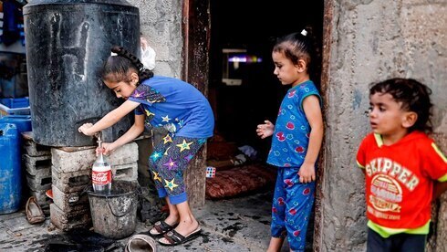 Niños cargan agua potable en una calle de Gaza. 