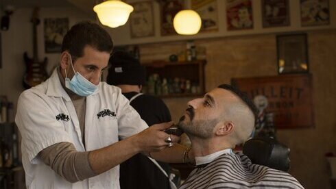 Un cliente se atiende en una barbería tras el alivio de las restricciones por coronavirus en Jerusalem. 