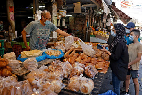 En el Mercado Mehane Yehuda, de Jerusalem, tanto comerciantes como clientes usan mascarillas protectoras al aire libre. 